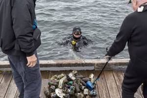 A diver volunteer empties the trash he was collected onto the dock at Davies Beach on Sunday, May 23, 2021 in Lake Stevens, Wash. (Olivia Vanni / The Herald)