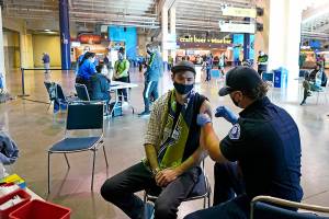 FILE - In this May 2, 2021, file photo, Austin Kennedy, left, a Seattle Sounders season ticket holder, gets the Johnson & Johnson COVID-19 vaccine at a clinic in a concourse at Lumen Field prior to an MLS soccer match between the Sounders and the Los Angeles Galaxy. Air travel in the U.S. hit its highest mark since COVID-19 took hold more than 13 months ago, while European Union officials are proposing to ease restrictions on visitors to the continent as the vaccine rollout sends new cases and deaths tumbling in more affluent countries. (AP Photo/Ted S. Warren, File)