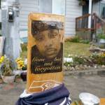 A sign that reads "Gone but not forgotten" is shown on a cross displayed Thursday, May 27, 2021, at a memorial that has been established at the intersection in Tacoma, Wash., south of Seattle, where Manuel "Manny" Ellis died on March 3, 2020, after he was restrained by police officers. Earlier in the day, the Washington state attorney general filed criminal charges against three police officers in the death of Ellis, a Black man who died after telling the Tacoma officers who were restraining him he couldn't breathe. (AP Photo/Ted S. Warren)