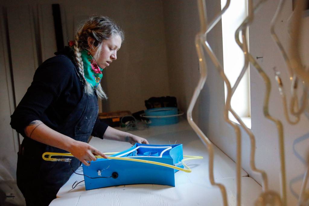 Sage Leonard assembles a neon art piece for an exhibit. She was taught by her dad, Tim Leonard. (Kevin Clark / The Herald)