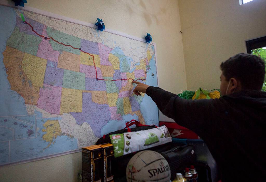 Deven Boyce, 14, points out designated stop locations along the route on a map at his Mukilteo home before leaving on the cross-country ride. (Olivia Vanni / The Herald)
