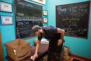 Jackson Quall, grandson of former owner Martha Quall, wipes down surfaces in preparation for re-opening on Saturday, May 29, 2021 in Everett, Wash. (Olivia Vanni / The Herald)