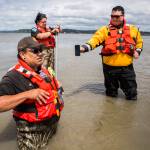 Shawn Edge (left), Robert Guss (center) and Robert Lee McCracken (right) try to locate on a cellphone where Shawn Edge and Charlie Cortez fell in the water, on May 28 in Possession Sound. (Olivia Vanni / The Herald)