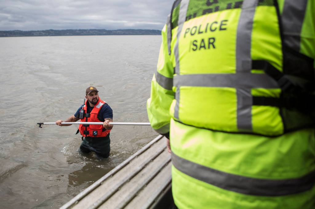 Beau Jess walks on a sandbar as people get out of the boat to start their search for Charlie Cortez on May 28 in Possession Sound. (Olivia Vanni / The Herald)
