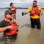 Shawn Edge, left, Robert Guss, center, Robert Lee McCracken, right, try to locate on a cellphone where Shawn Edge and Charlie Cortez fell in the water on Friday, May 28, 2021 in Possession Sound, Wash. (Olivia Vanni / The Herald)
