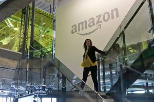 FILE - In this Sept. 27, 2017, file photo, an Amazon worker walks down steps in a company office before an event announcing several new Amazon products by the company in Seattle. Amazon plans to have its employees return to the office by fall as the tech giant transitions away from the remote work it implemented for many workers due to the coronavirus pandemic. On Tuesday, March 30, 2021, the company told employees it is planning a "return to an office-centric culture as our baseline." (AP Photo/Elaine Thompson, File)