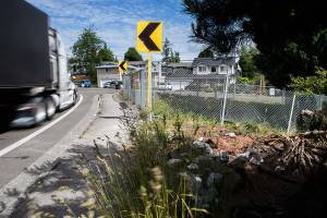 A tractor-trailer drives by a damaged fence surrounding a stormwater detention pond along Fourth Street on Friday, June 4, 2021 in Everett, Wash. (Olivia Vanni / The Herald)