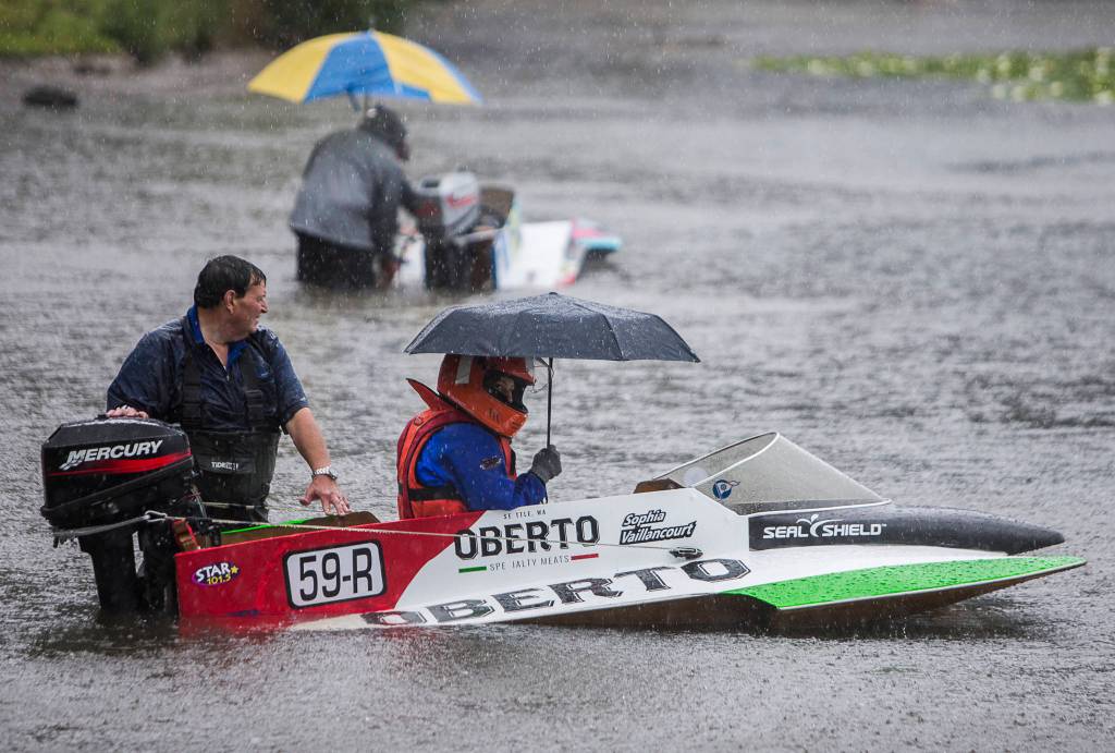 Sophia Vaillancourt sits in her mini hydroplane under an umbrella while her father, Dave Vaillancourt, holds her boat in place as they wait for her race to be announced on Saturday, June 5, 2021 in Everett, Wash. (Olivia Vanni / The Herald)