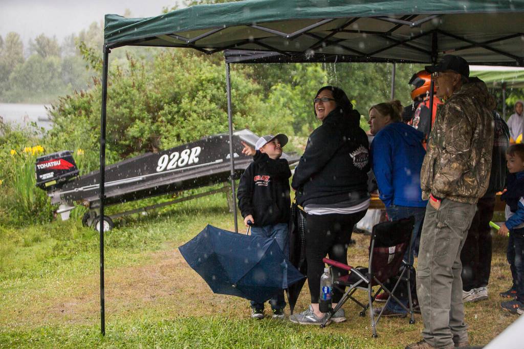 Spectators watch races from the shelter of their canopy as a rainstorm passes through during the Silver Lake Regatta on Saturday, June 5, 2021 in Everett, Wash. (Olivia Vanni / The Herald)