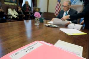 Washington Gov. Jay Inslee uses a red pen to veto sections of the state capital budget, Tuesday, May 21, 2019, at the Capitol in Olympia, Wash. Inslee signed the state's capital, operating, and transportation budgets Tuesday, officially designating funds — and new taxes — to pay for state programs for the next two years. (AP Photo/Ted S. Warren)