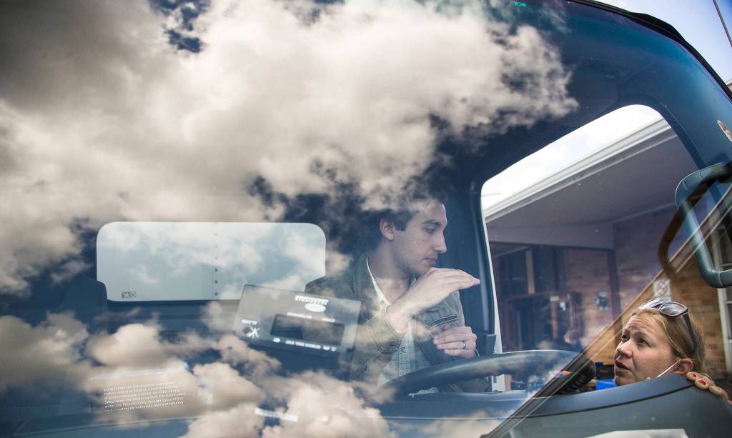 Ryan Whitton, executive director of the Granite Falls Food Bank, shows Ellen Panagos how to turn on the refrigeration unit in a truck. (Andy Bronson / The Herald)