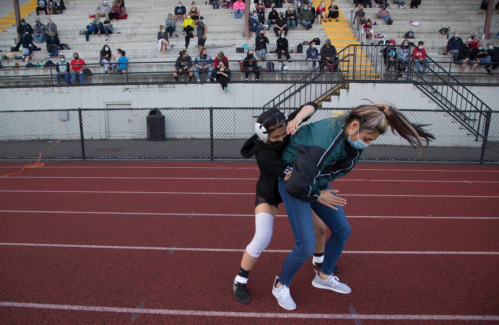Jacksons Jocelyn Villa goes over moves with her coach, Chey Kawaihae, before her match at a girls wrestling scramble held outside at Marysville Pilchuck High School on Tuesday in Marysville. (Andy Bronson / The Herald)
