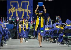 Mariner High School graduate Careana Willis raises her diploma in the air Saturday as she walks back to her seat during graduation at Angel of the Winds Arena in Everett. (Olivia Vanni / The Herald)