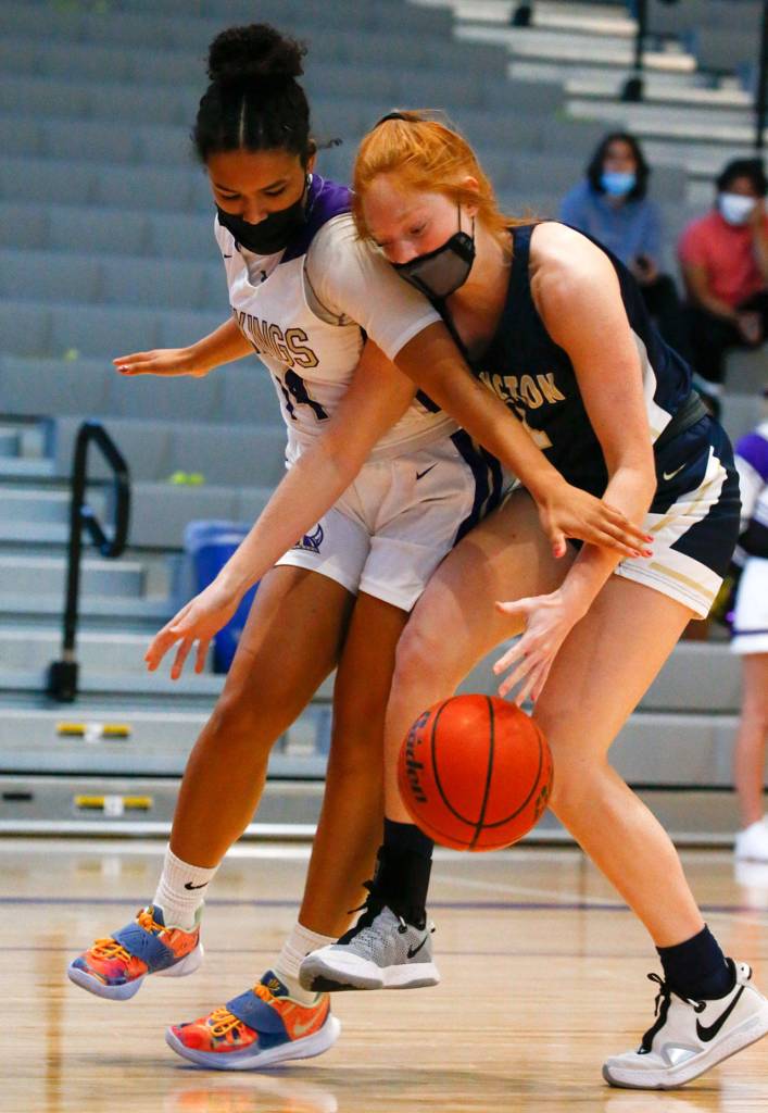 Lake Stevens Baylor Thomas (left) and Arlingtons Makenzie Gage vie for control of the ball during a game on Wednesday evening at Lake Stevens High School. Arlington won 80-71. (Kevin Clark / The Herald)