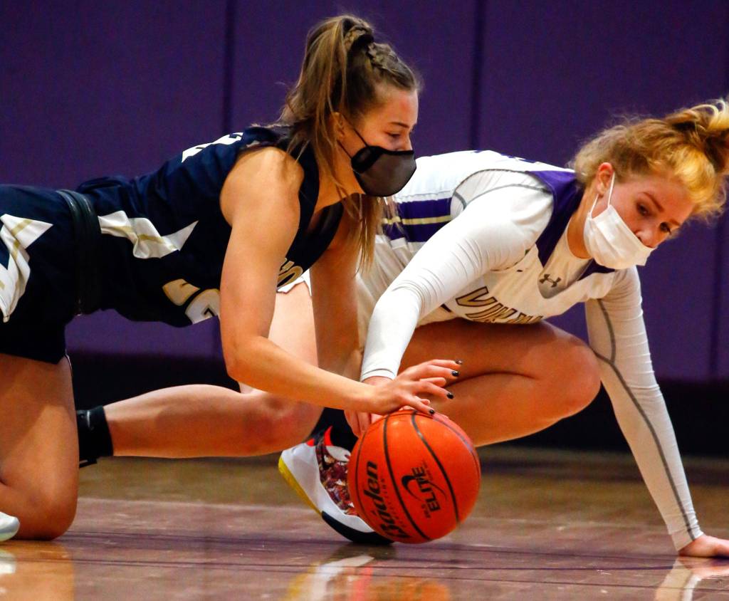 Arlingtons Ella Stritmatter (left) and Lake Stevens Cori Wilcox dive for a loose ball during a game on Wednesday evening at Lake Stevens High School. Arlington won 80-71. (Kevin Clark / The Herald)