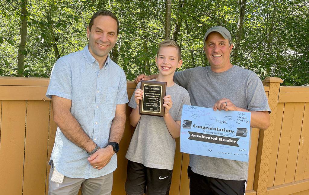 Champion reader Willem Wolters poses with Cedar Wood Elementary School librarian Mark Smith (left) and fourth-grade teacher John Pappas. (Marisa Wolters)