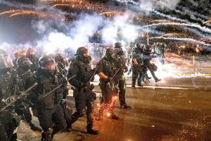 FILE - In this Sept. 5, 2020, file photo, police use chemical irritants and crowd control munitions to disperse protesters during a demonstration in Portland, Ore. City officials insist Portland is resilient as they launch a revitalization plan — in the form of citywide cleanups of protest damage, aggressive encampment removals, increased homeless services and police reform — to repair its reputation. (AP Photo/Noah Berger)