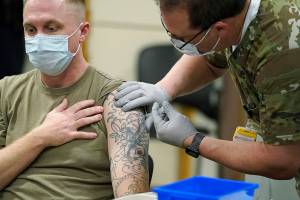 FILE - In this Dec. 16, 2020, file photo, Staff Sgt. Travis Snyder, left, receives the first dose of the Pfizer COVID-19 vaccine given at Madigan Army Medical Center at Joint Base Lewis-McChord in Washington state, south of Seattle. Nurse Jose Picart, right, administered the shot. Washington Gov. Jay Inslee on Thursday, June 17, 2021, announced a new COVID-19 vaccine incentive lottery for the state's military, family members and veterans because the federal government wasn't sharing individual vaccine status of those groups with the state and there were concerns they would be left out of a previously announced lottery. (AP Photo/Ted S. Warren, File)