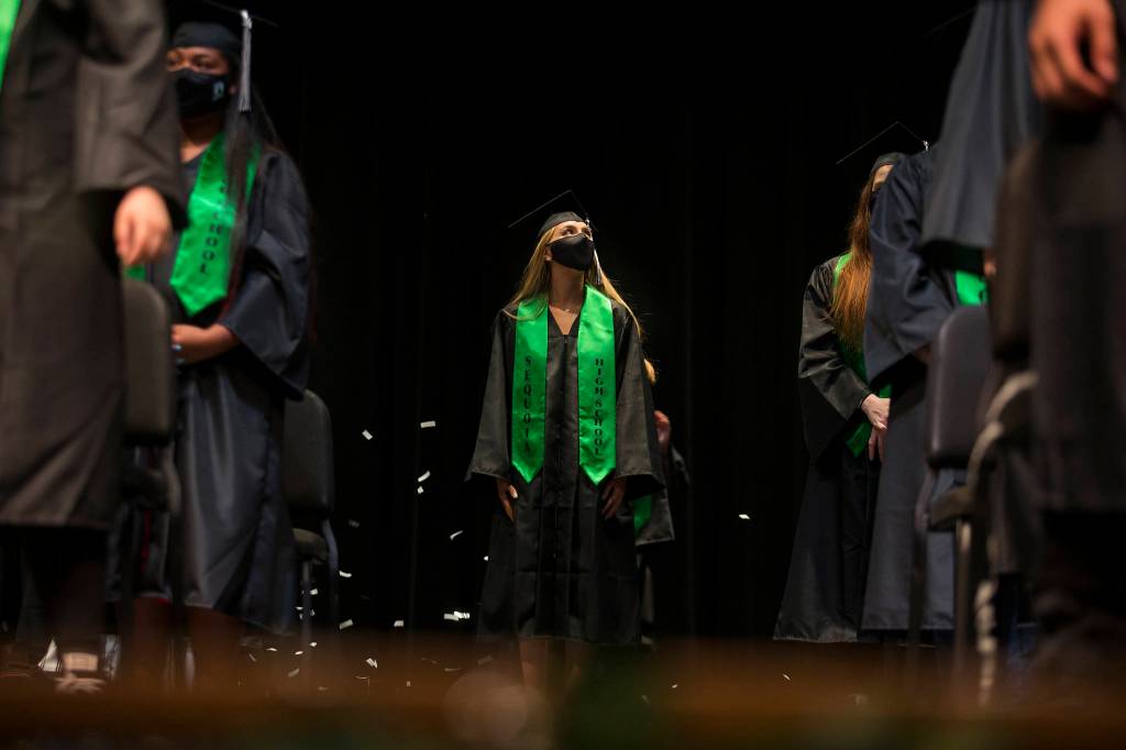 A Sequoia High graduates looks up as the last confetti strips fall at the end of the graduation ceremony Thursday in Everett. (Andy Bronson / The Herald)
