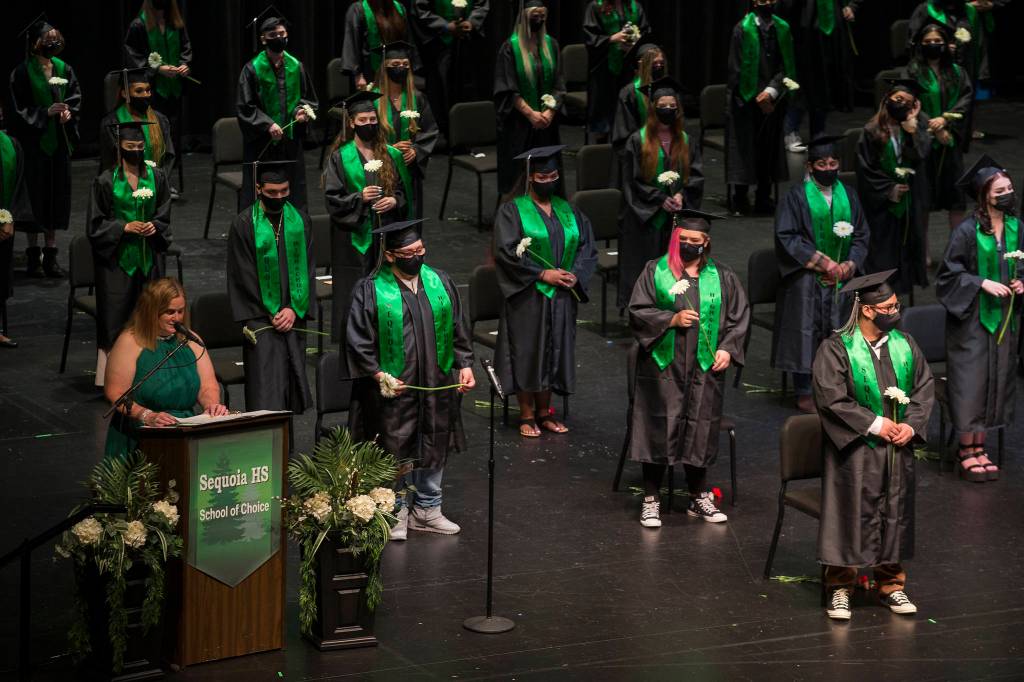 Sequoia High graduates are socially distanced on stage as principal Kelly Shepard gets the graduation ceremony started Thursday in Everett. (Andy Bronson / The Herald)