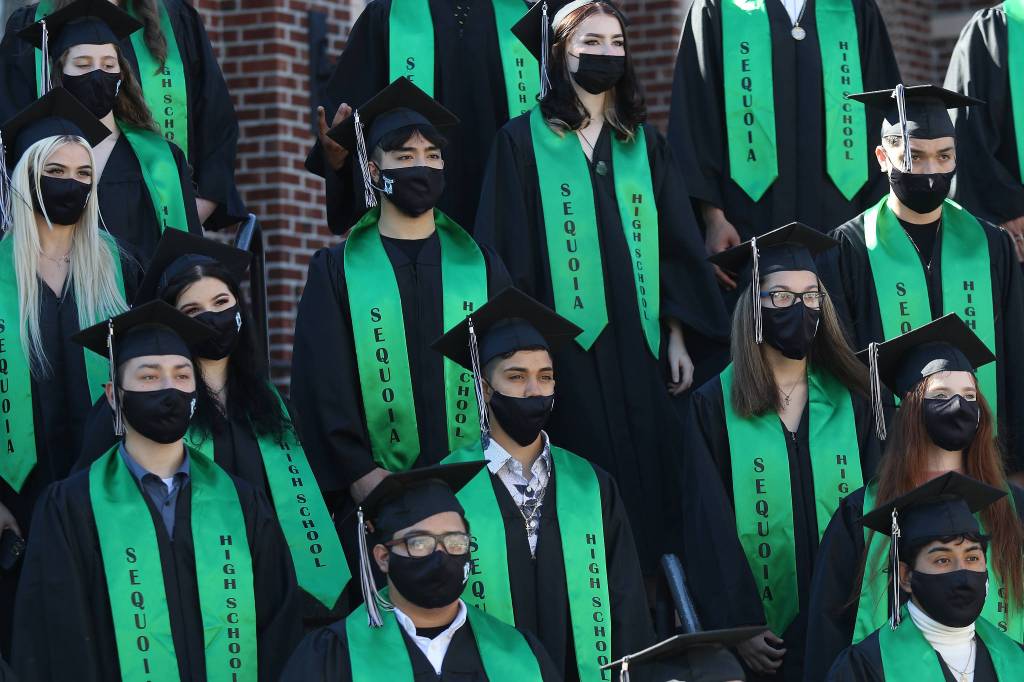 With masks on, graduates are asked to smile during a class photo before Sequoia High holds its graduation ceremony Thursday in Everett. (Andy Bronson / The Herald)