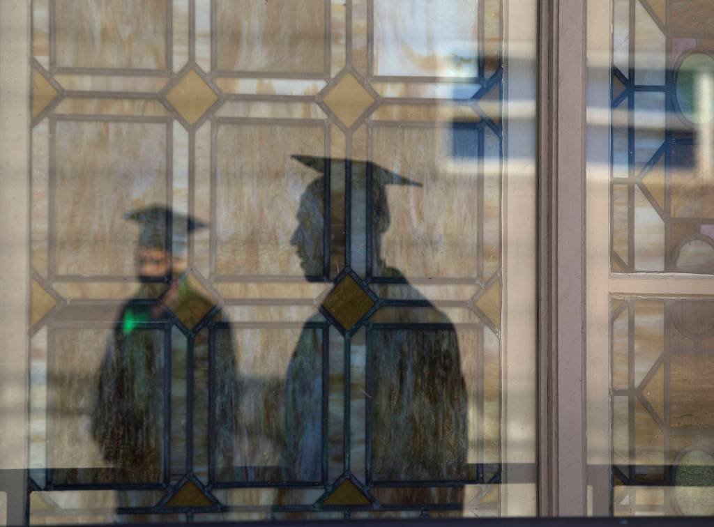 Sequoia High graduates are reflected in the windows of the Little Theater before their graduation ceremony Thursday in Everett. (Andy Bronson / The Herald)