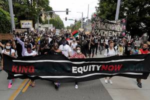 FILE - In this June 19, 2020, file photo, people taking part in a Juneteenth march travel down 23rd Ave. in Seattle. President Joe Biden this week signed legislation establishing a new federal holiday commemorating the end of slavery – a move lawmakers made for Washington state earlier this year. Washington Gov. Jay Inslee last month signed a measure making Juneteenth a legal state paid holiday, starting in 2022. (AP Photo/Ted S. Warren, File)