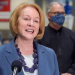 Seattle Mayor Jenny Durkan speaks at a news conference as Washington Gov. Jay Inslee looks on, Wednesday, March 10, 2021, at the Lumen Field Events Center in Seattle. Durkan and other officials announced Wednesday that a mass COVID-19 vaccination site would begin operation at the facility Saturday, and said it would be the largest civilian-led vaccination site in the country. Lumen Field is the home stadium of the Seattle Seahawks NFL football team and the Seattle Sounders MLS soccer team. (AP Photo/Ted S. Warren)