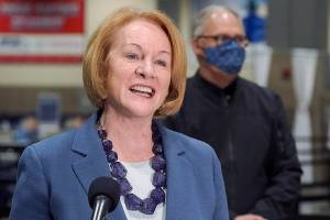 Seattle Mayor Jenny Durkan speaks at a news conference as Washington Gov. Jay Inslee looks on, Wednesday, March 10, 2021, at the Lumen Field Events Center in Seattle. Durkan and other officials announced Wednesday that a mass COVID-19 vaccination site would begin operation at the facility Saturday, and said it would be the largest civilian-led vaccination site in the country. Lumen Field is the home stadium of the Seattle Seahawks NFL football team and the Seattle Sounders MLS soccer team. (AP Photo/Ted S. Warren)