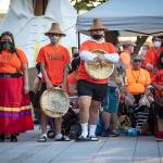 People listen during a ceremony and vigil for the 215 children whose remains were found buried at the former Kamloops Indian Residential School, in Vancouver, British Columbia, on National Indigenous Peoples Day, June 21. (Darryl Dyck/The Canadian Press via AP)