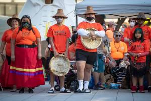 People listen during a ceremony and vigil for the 215 children whose remains were found buried at the former Kamloops Indian Residential School, in Vancouver, British Columbia, on National Indigenous Peoples Day, Monday, June 21, 2021. (Darryl Dyck/The Canadian Press via AP)