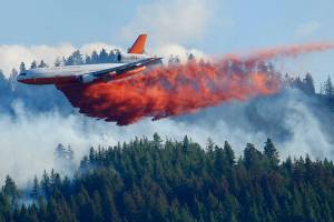 FILE - In this Aug. 21, 2015 file photo, a tanker airplane drops fire retardant on a wildfire burning near Twisp, Wash. Three firefighters were killed battling the blaze. The story was a top Washington state news item in 2015. Public Lands Commissioner Hilary Franz has proposed a plan to strengthen the ways that Washington can prevent and respond to wildfires. Franz released the 10-year plan last week as part of her $55 million budget request to the Legislature to improve the state's firefighting abilities (AP Photo/Ted S. Warren, File)