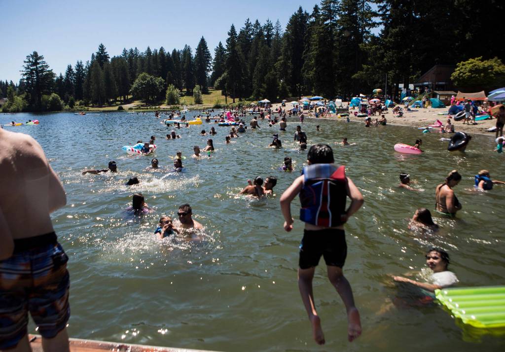 People swim and sit along Silver Lakes beach Saturday at Thornton A. Sullivan Parkin Everett. (Olivia Vanni / The Herald)