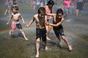 David Parada, 7, left, and Abel Parada, 8, run through a heavy spray of water creating a rainbow at Walter E. Hall Park on Saturday, June 26, 2021 in Everett, Wa. The Everett Fire Department set up a fire hose sprinkler station to help people cool down and escape the heat Saturday afternoon. (Olivia Vanni / The Herald)