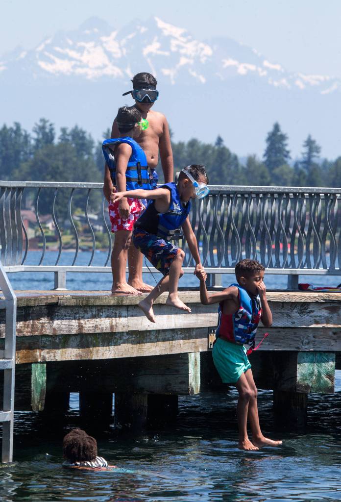 Kairee DeGrant, 7, leads Liam Dittrick, 4, into Lake Stevens at Davies Beach (formerly Willard Wyatt Park) on Tuesday. (Andy Bronson / The Herald)