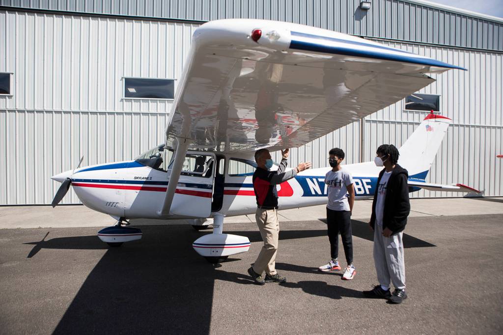 Red-Tailed Hawks Flying Club members talk with a pilot before flights at Arlington Municipal Airport. (Olivia Vanni / The Herald)