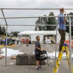 Jeff Irtter (left) and Tom Glasenapp dismantle a tent at the COVID vaccination station at the Evergreen State Fairgrounds in Monroe. (Kevin Clark / The Herald)