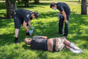 With the temperature well over 100 degrees, Spokane, Wash., firefighter Sean Condon, left and Lt. Gabe Mills, assigned to the Alternative Response Unit of of Station 1, check on the welfare of a man in Mission Park in Spokane, Wash., Tuesday, June 29, 2021. The special fire unit, which responds to low priority calls, has been kept busy during this week's heatwave. (Colin Mulvany/The Spokesman-Review via AP)
