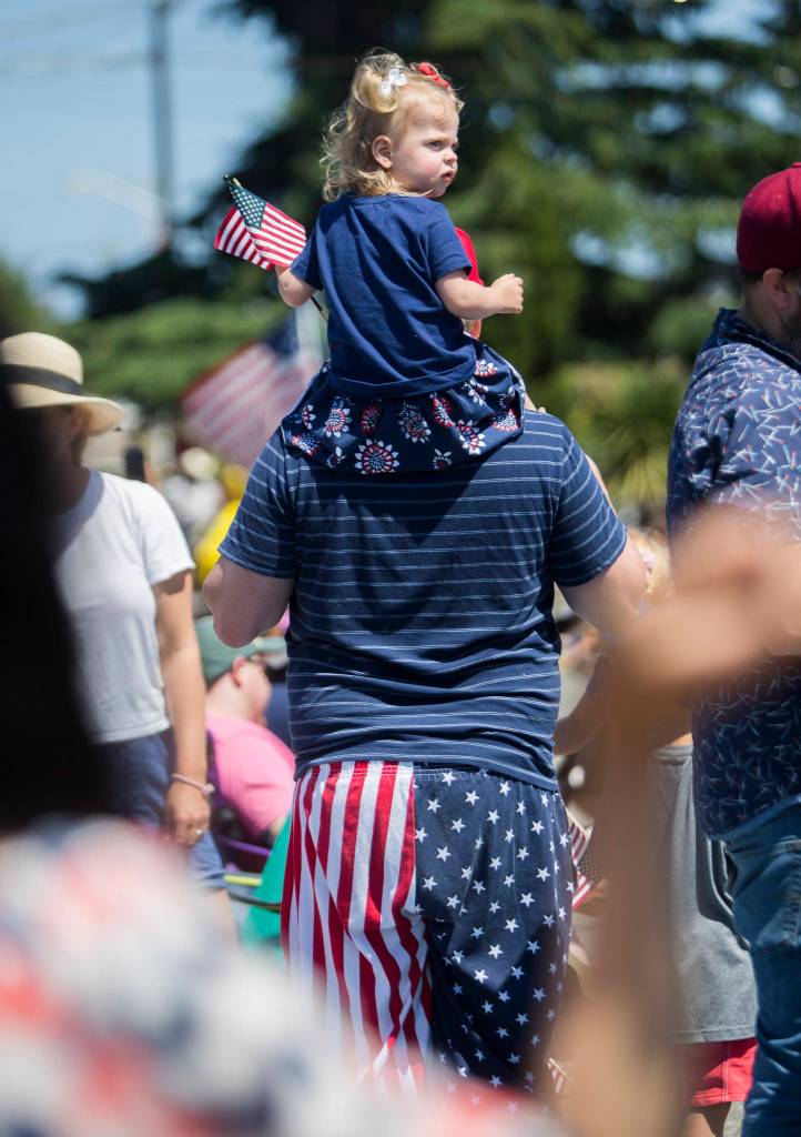 Justin Farris and his daughter, Milla, 2, watch the Edmonds Kind of 4th parade on Sunday in Edmonds. (Olivia Vanni / The Herald)