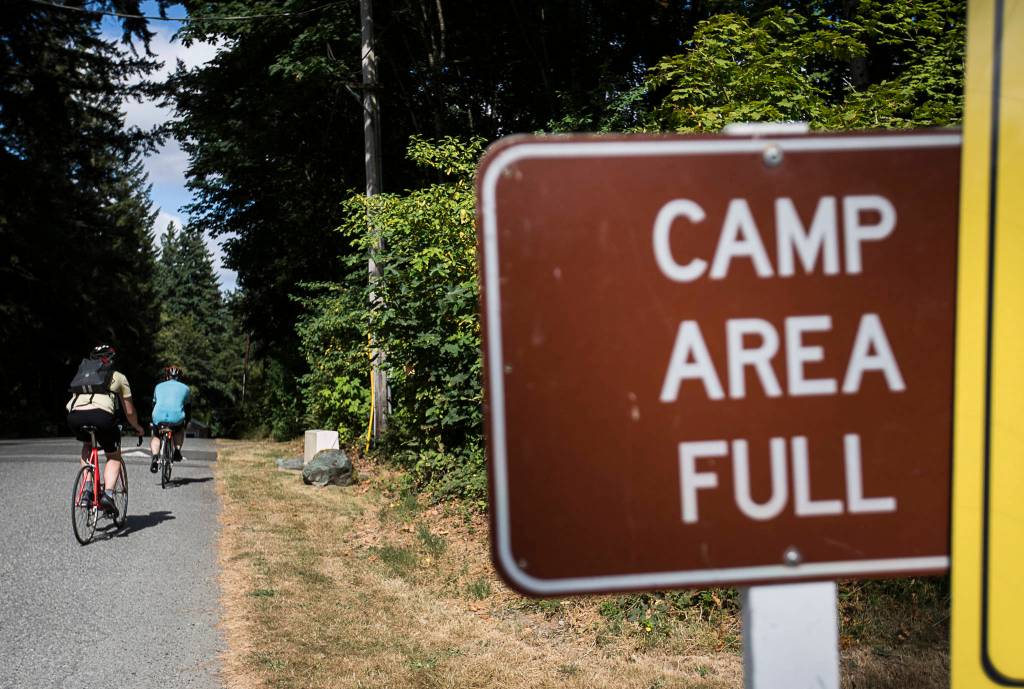 Ben Watanabe and Zachariah Bryan ride into a full campground at Wenberg County Park on Saturday near Stanwood. A weekday bus can deliver campers less than two miles away on Highway 531. (Olivia Vanni / The Herald)