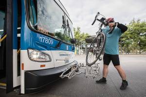 Street Smarts columnist Ben Watanabe places his bike onto the Community Transit 201 bus rack on Saturday, July 17, 2021 in Everett, Wash. (Olivia Vanni / The Herald)