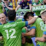 Sounders players, including Brad Smith (left), and Fredy Montero (12), surround forward Raul Ruidiaz (obscured) after Ruidiaz scored a goal against the Dynamo during the second half of an MLS match on July 7, 2021, in Seattle. The Sounders won 2-0. (AP Photo/Ted S. Warren)
