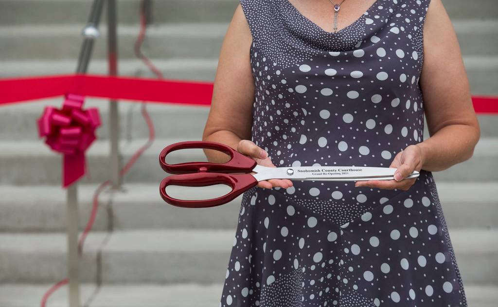 Lolly Huggins holds commemorative scissors before a ribbon-cutting ceremony to mark the completion of the Snohomish County Courthouse remodel and addition project Thursday in Everett. (Andy Bronson / The Herald)