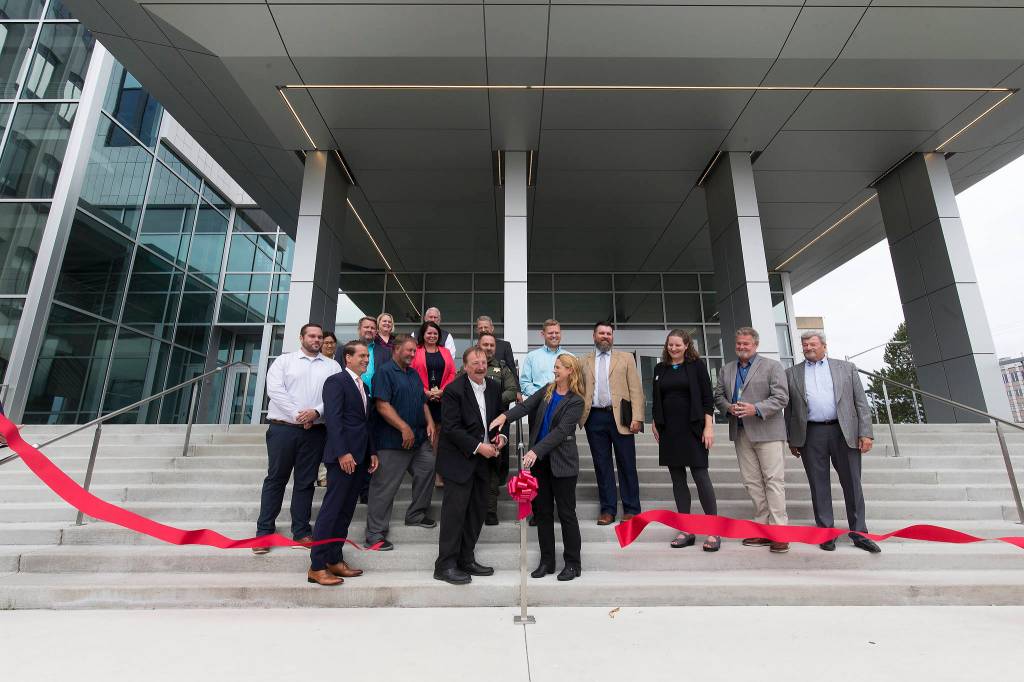 Surrounded by Snohomish County leaders and representatives from labor, construction companies and others, Snohomish County Executive Dave Somers and County Council Chair Stephanie Wright cut a ribbon to mark the completion of the Snohomish County Courthouse remodel and addition project Thursday in Everett. (Andy Bronson / The Herald)