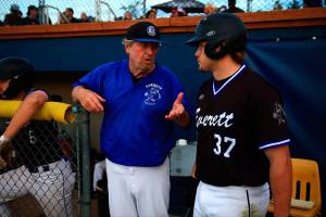 Merchants coach Harold Pyatte (left) and Jaxsen Sweum chat in the dugout during the 116th Midnight Sun Game against the Goldpanners on June 21 in Fairbanks, Alaska. (Photo by Justin Prax)