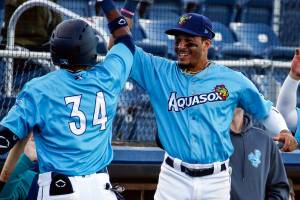 AquaSoxs Miguel Perez (left) is greeted at the dug out by teammate Joseph Rosa Thursday evening at Funko Field in Everett on June 3, 2021. (Kevin Clark / The Herald)