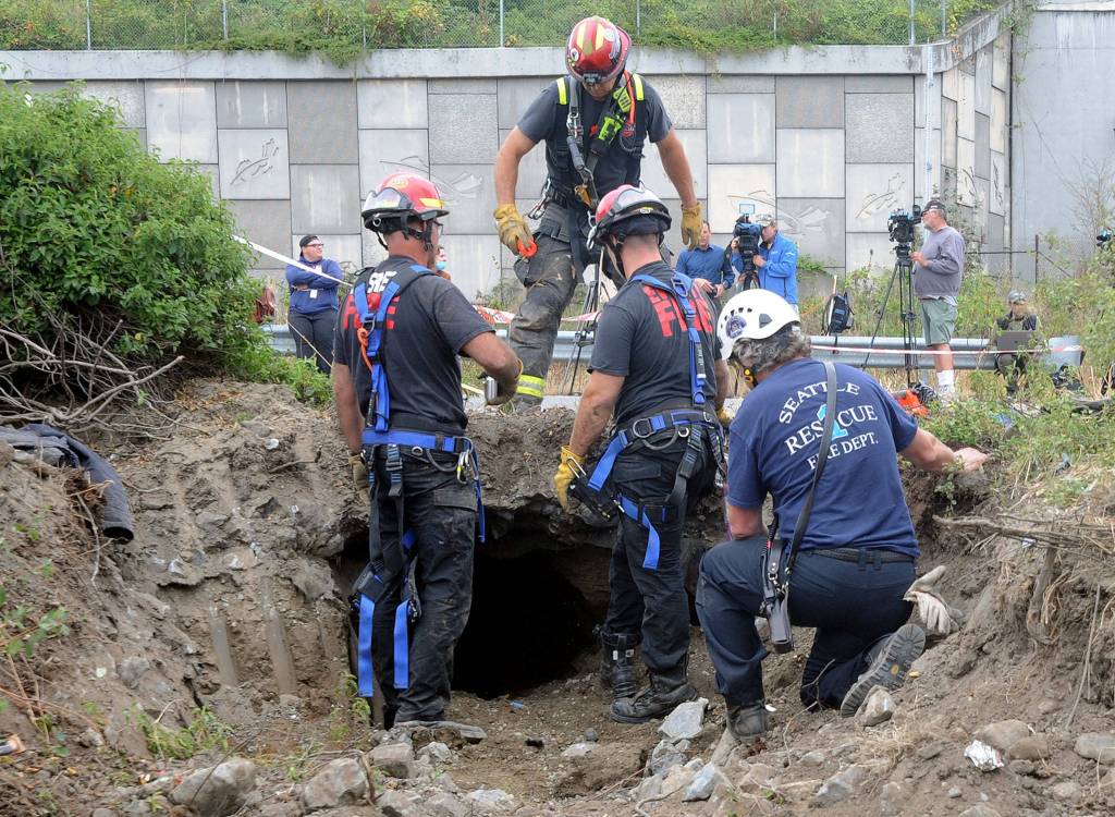 Members of the Everett and Seattle fire departments technical rescue teams strategize how much farther to dig as they search a tunnel that was dug under the northbound I-5 off-ramp to Pacific Avenue on Thursday in Everett. (Doug Ramsay / For The Herald)