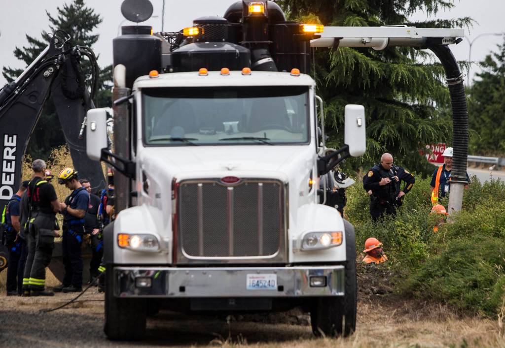 An Everett Public Works excavator helps move dirt from a possible tunnel collapse along I-5 at Pacific Avenue on Thursday. (Olivia Vanni / The Herald)