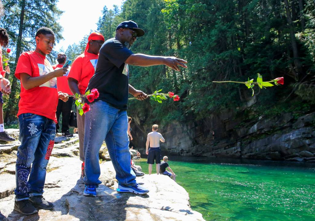 Marvin Shelby tosses a rose into the Skykomish River at Eagle Falls in memory of his son, Devin Shelby. (Kevin Clark / The Herald)