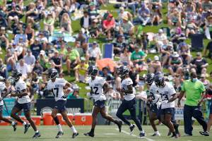 Seattle Seahawks defensive players run on the field as fans watch NFL football practice Wednesday, July 28, 2021, in Renton, Wash. (AP Photo/Ted S. Warren)